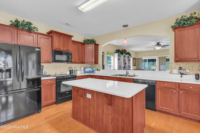 5170 Swashbuckler Way, Southport, NC 28461 - kitchen with black appliances, a sink, arched walkways, a kitchen island, and light wood finished floors