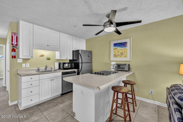 404 S Carolina Beach Ave Unit B7, Carolina Beach, NC 28428 - kitchen with black appliances, a kitchen breakfast bar, white cabinetry, a ceiling fan, and light countertops