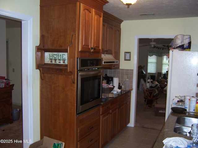 125 Pinehurst Trace Dr, Pinehurst, NC 28374 - kitchen featuring oven, backsplash, light tile patterned floors, range hood, and dark countertops