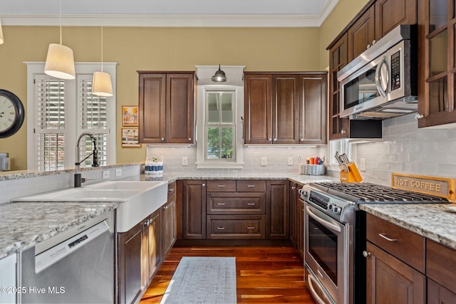 401 Fire Fly Ln, Southport, NC 28461 - kitchen with stainless steel appliances, dark wood-style flooring, tasteful backsplash, ornamental molding, and light stone counters
