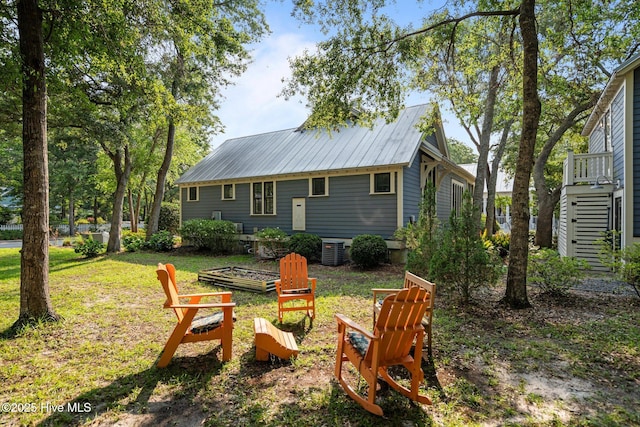 401 Fire Fly Ln, Southport, NC 28461 - back of property featuring a fire pit, central air condition unit, metal roof, and a yard