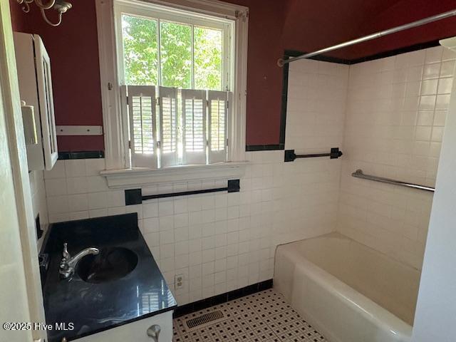 1041 Lafayette Ave, Rocky Mount, NC 27803 - bathroom featuring tile walls, vanity, a wainscoted wall, shower / washtub combination, and tile patterned floors