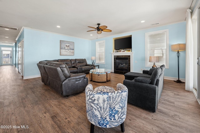 living area with ornamental molding, a ceiling fan, wood finished floors, recessed lighting, and a fireplace
