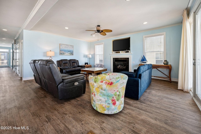 living area featuring crown molding, a fireplace, dark wood-style flooring, ceiling fan, and recessed lighting
