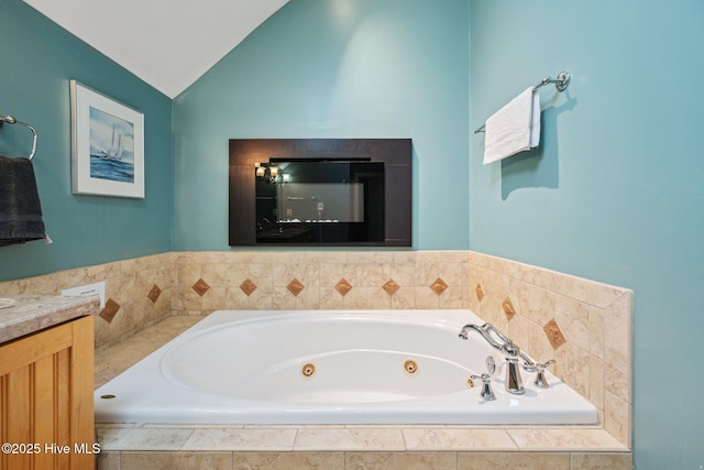 full bathroom featuring a tub with jets, vaulted ceiling, and vanity
