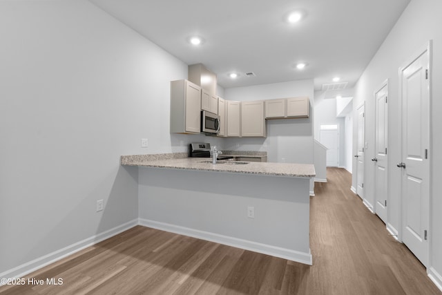 796 Palm Frond Way Unit 47, Calabash, NC 28467 - kitchen with stainless steel appliances, wood finished floors, a peninsula, baseboards, and a sink