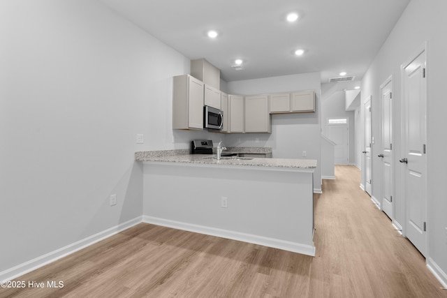 796 Palm Frond Way Unit 47, Calabash, NC 28467 - kitchen with stainless steel appliances, light wood-type flooring, a peninsula, a sink, and baseboards