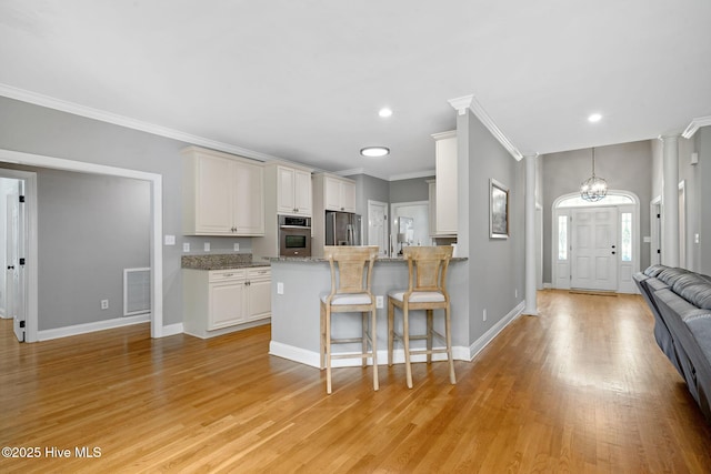 224 Red Fox Run Dr, Wallace, NC 28466 - kitchen with appliances with stainless steel finishes, crown molding, a kitchen breakfast bar, light wood-style floors, and a chandelier