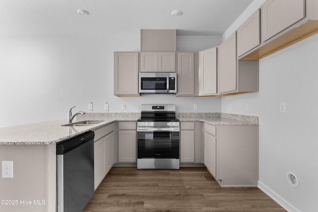 776 Palm Frond Way Unit 55, Calabash, NC 28467 - kitchen with stainless steel appliances, a sink, a peninsula, wood finished floors, and light stone counters