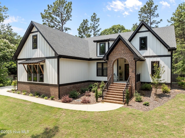 499 Longleaf Dr, West End, NC 27376 - view of front facade featuring roof with shingles, brick siding, a front yard, and board and batten siding