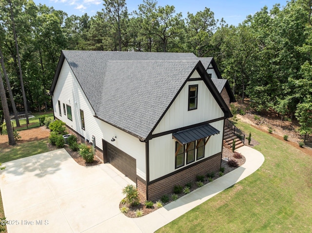499 Longleaf Dr, West End, NC 27376 - view of front facade featuring a shingled roof, a front lawn, concrete driveway, board and batten siding, and an attached garage