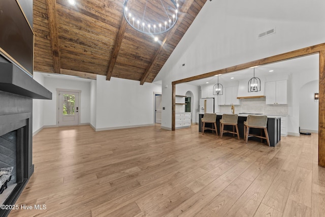 499 Longleaf Dr, West End, NC 27376 - living area with a fireplace, a chandelier, light wood finished floors, high vaulted ceiling, and wood ceiling with exposed beams