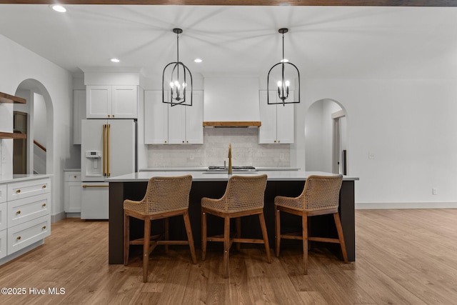 499 Longleaf Dr, West End, NC 27376 - kitchen featuring white refrigerator with ice dispenser, custom range hood, tasteful backsplash, light countertops, and an island with sink