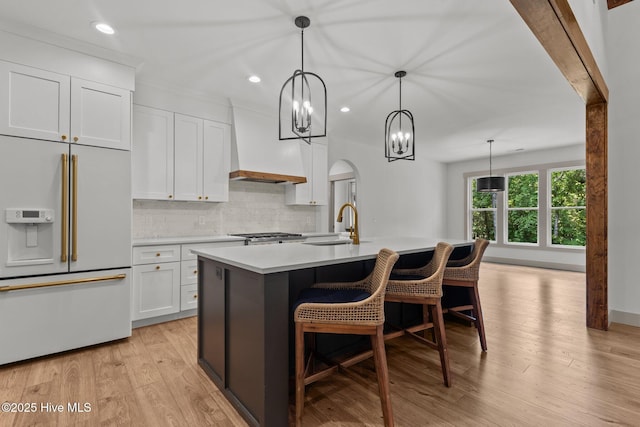 499 Longleaf Dr, West End, NC 27376 - kitchen with high end white refrigerator, premium range hood, light countertops, backsplash, and a center island with sink