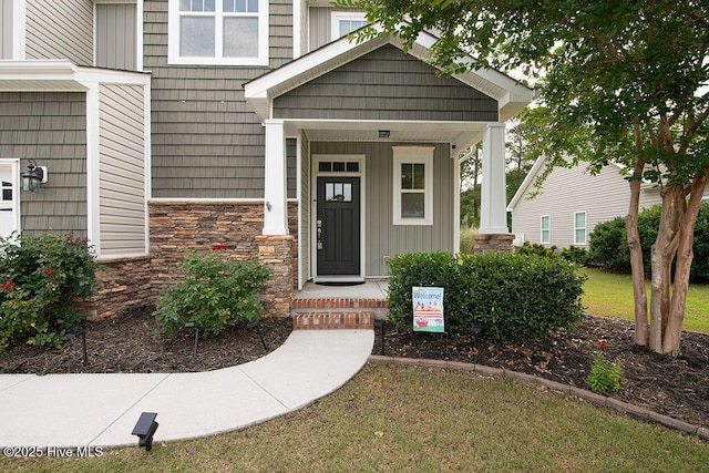 472 Landsdowne Cir, Hampstead, NC 28443 - view of exterior entry featuring stone siding, board and batten siding, a lawn, and a porch