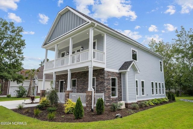 505 N Shore Dr, Sneads Ferry, NC 28460 - view of front facade featuring a porch, a balcony, board and batten siding, a front yard, and stone siding