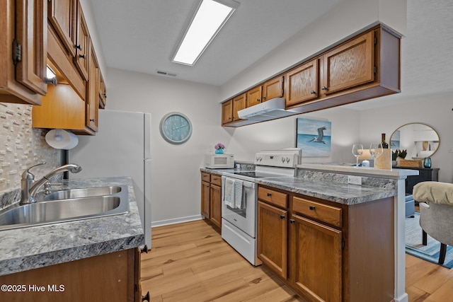 9100 Reed Dr Unit 3107, Emerald Isle, NC 28594 - kitchen with white appliances, a sink, under cabinet range hood, light wood finished floors, and brown cabinetry