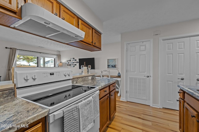 9100 Reed Dr Unit 3107, Emerald Isle, NC 28594 - kitchen featuring white electric stove, extractor fan, brown cabinets, light wood-style flooring, and light countertops