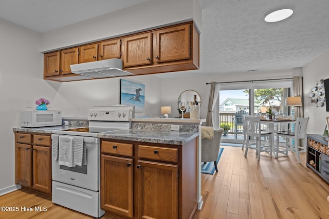 9100 Reed Dr Unit 3107, Emerald Isle, NC 28594 - kitchen with white appliances, under cabinet range hood, brown cabinets, and a textured ceiling