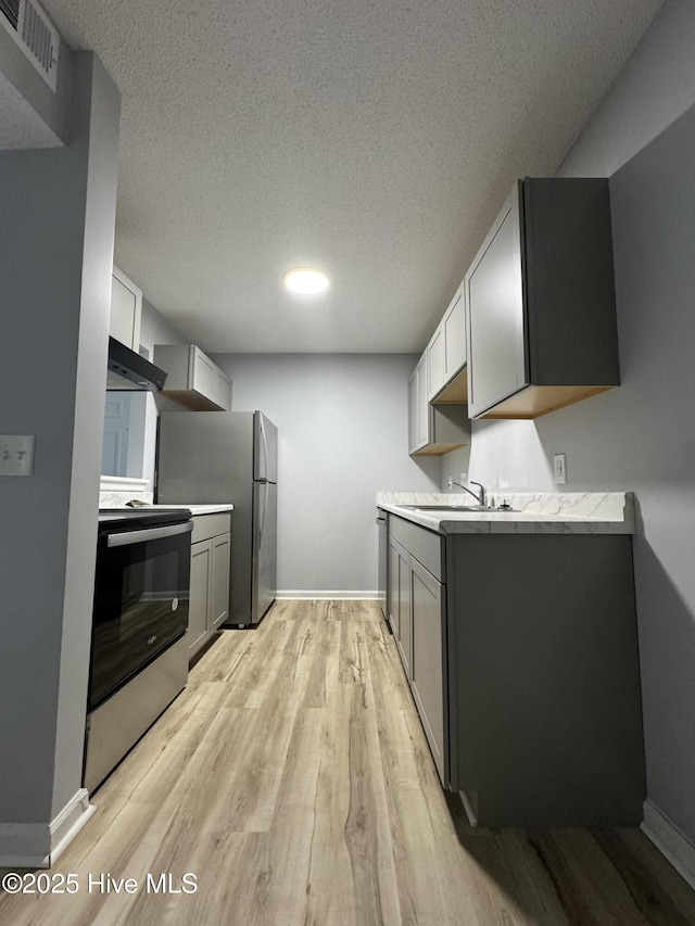 5633 Hornaday Rd Unit C, Greensboro, NC 27409 - kitchen featuring stainless steel appliances, wall chimney exhaust hood, a sink, light countertops, and light wood-style floors
