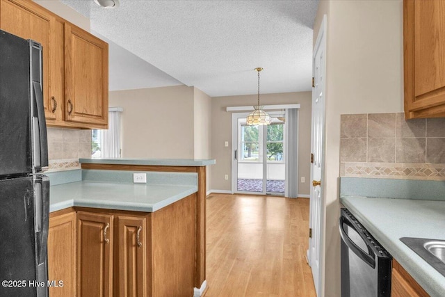 734 Sloop Pointe Ln, Kure Beach, NC 28449 - kitchen with freestanding refrigerator, dishwashing machine, light wood finished floors, brown cabinetry, and backsplash