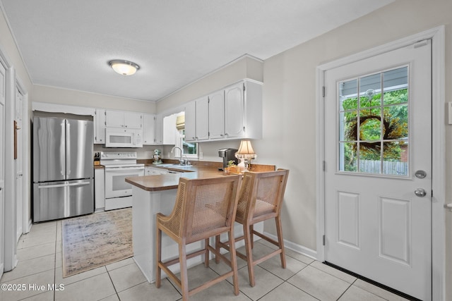 114 Mohican Trl, Wilmington, NC 28409 - kitchen with white appliances, a peninsula, a sink, light tile patterned floors, and white cabinets