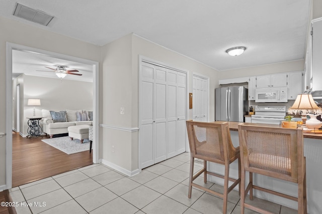 114 Mohican Trl, Wilmington, NC 28409 - kitchen with white appliances, white cabinetry, light tile patterned floors, ceiling fan, and a peninsula