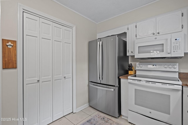 114 Mohican Trl, Wilmington, NC 28409 - kitchen featuring white appliances, ornamental molding, light tile patterned floors, white cabinets, and dark countertops