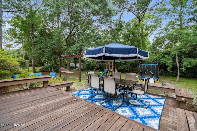 114 Mohican Trl, Wilmington, NC 28409 - wooden deck with a trampoline, a playground, outdoor dining area, and view of wooded area