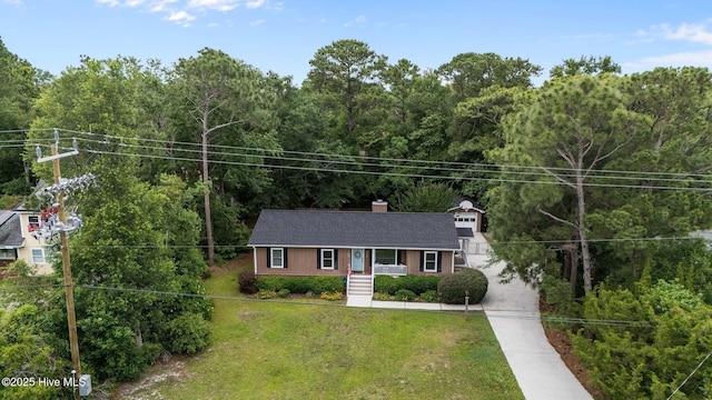 114 Mohican Trl, Wilmington, NC 28409 - ranch-style home featuring a front lawn, concrete driveway, a chimney, and a wooded view