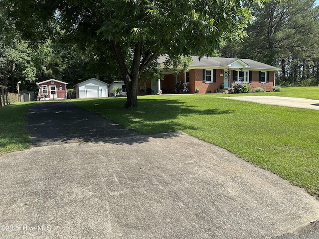 127 Deans Ln, Goldsboro, NC 27530 - ranch-style house with driveway, a front lawn, an outbuilding, a garage, and brick siding
