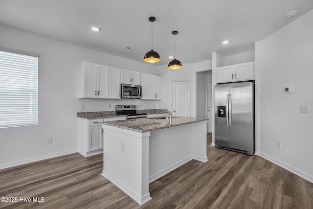 1617 Stanley St, Wilmington, NC 28401 - kitchen featuring appliances with stainless steel finishes, white cabinets, dark wood finished floors, hanging light fixtures, and an island with sink