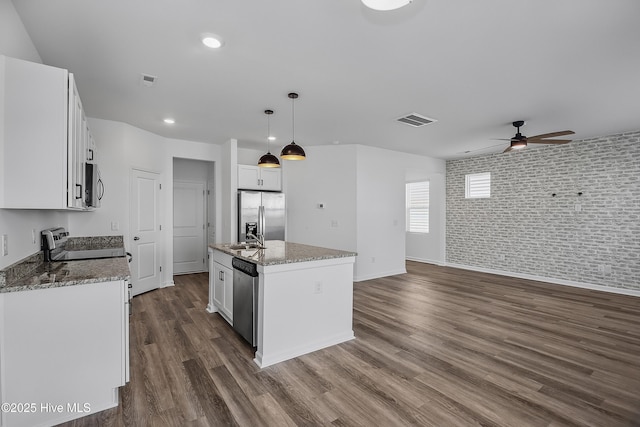 1617 Stanley St, Wilmington, NC 28401 - kitchen with stainless steel appliances, a ceiling fan, white cabinets, an island with sink, and brick wall
