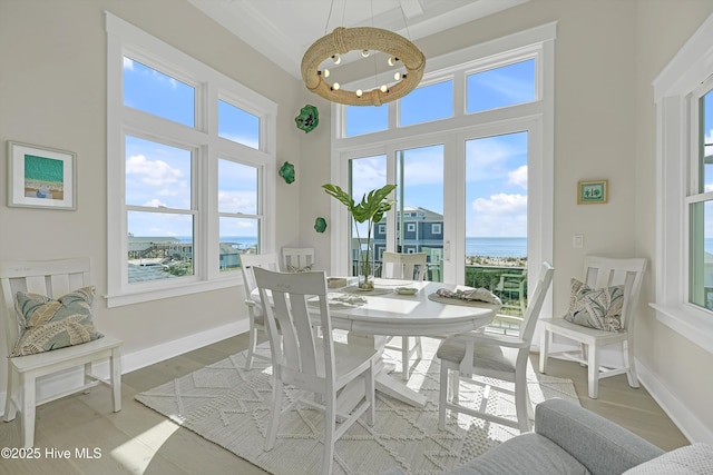 4920 E Beach Dr, Oak Island, NC 28465 - dining area featuring a water view, a high ceiling, light wood-style floors, baseboards, and a chandelier