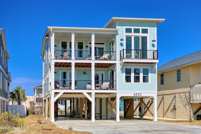 4920 E Beach Dr, Oak Island, NC 28465 - back of house featuring a carport, a balcony, and driveway