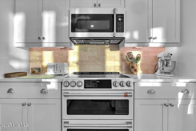 4920 E Beach Dr, Oak Island, NC 28465 - kitchen featuring appliances with stainless steel finishes, light countertops, tasteful backsplash, and white cabinetry