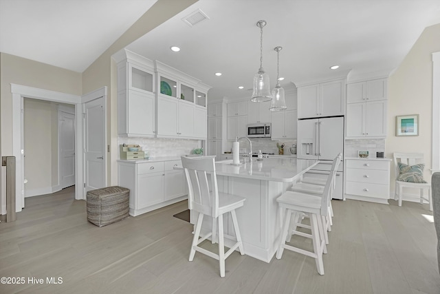 4920 E Beach Dr, Oak Island, NC 28465 - kitchen featuring stainless steel microwave, light countertops, white cabinets, light wood-type flooring, and decorative backsplash