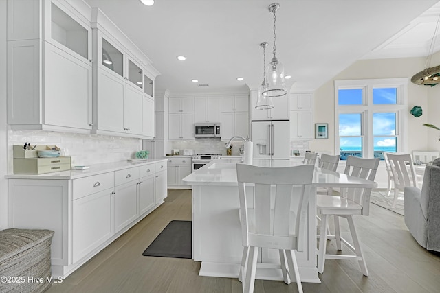 4920 E Beach Dr, Oak Island, NC 28465 - kitchen with high quality fridge, stainless steel microwave, white cabinetry, light wood-style floors, and backsplash