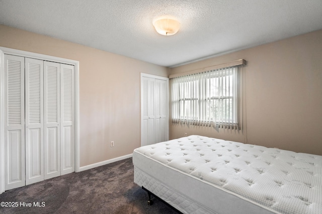 280 Cornwallis Rd, Teachey, NC 28464 - bedroom with multiple closets, dark carpet, and a textured ceiling