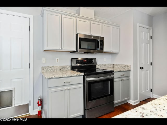 406 Endicott Ct, Wilmington, NC 28411 - kitchen with stainless steel appliances, dark wood-style flooring, light stone countertops, baseboards, and white cabinetry