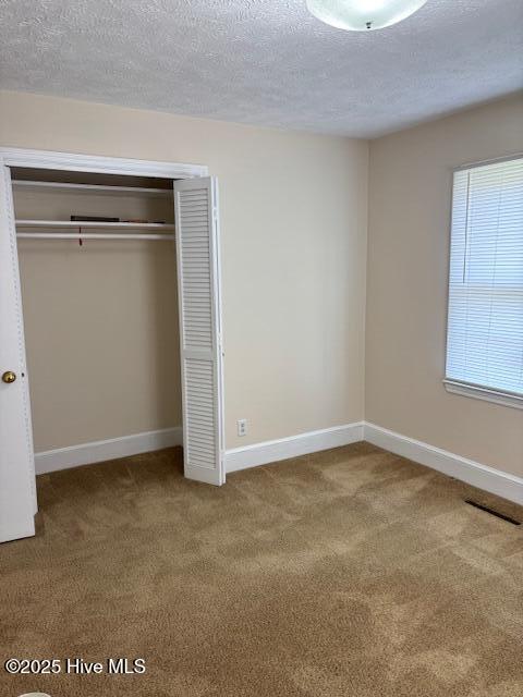 908 E 7th St, Lumberton, NC 28358 - unfurnished bedroom with a textured ceiling, carpet flooring, and a closet