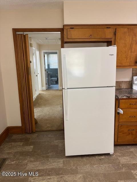 908 E 7th St, Lumberton, NC 28358 - kitchen with freestanding refrigerator, brown cabinets, and dark countertops