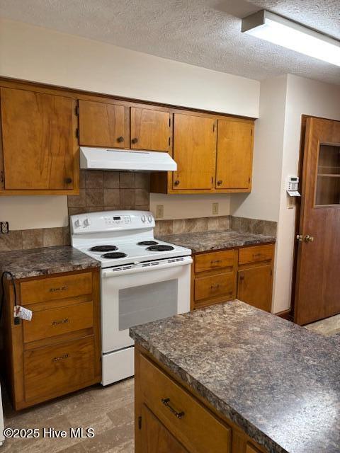908 E 7th St, Lumberton, NC 28358 - kitchen with white electric range oven, under cabinet range hood, dark countertops, brown cabinetry, and decorative backsplash
