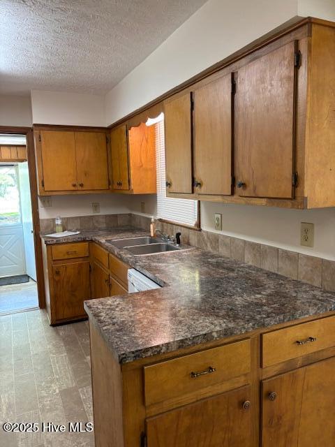 908 E 7th St, Lumberton, NC 28358 - kitchen featuring brown cabinetry, a textured ceiling, and a peninsula