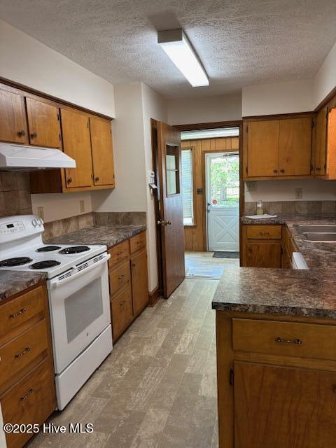 908 E 7th St, Lumberton, NC 28358 - kitchen featuring electric range, under cabinet range hood, dark countertops, and a textured ceiling