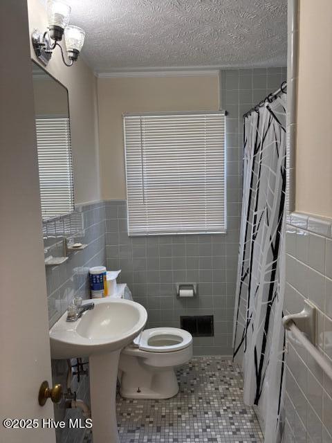 908 E 7th St, Lumberton, NC 28358 - full bath featuring tile walls, a shower with curtain, tile patterned flooring, a textured ceiling, and a wainscoted wall