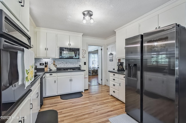 1409 Knollwood Dr NW, Wilson, NC 27896 - kitchen with black appliances, dark countertops, crown molding, light wood-style floors, and white cabinetry