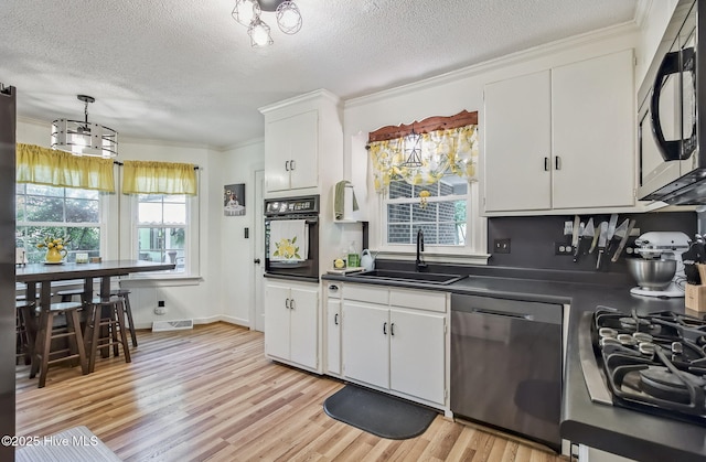 1409 Knollwood Dr NW, Wilson, NC 27896 - kitchen with stainless steel appliances, dark countertops, a sink, a textured ceiling, and crown molding