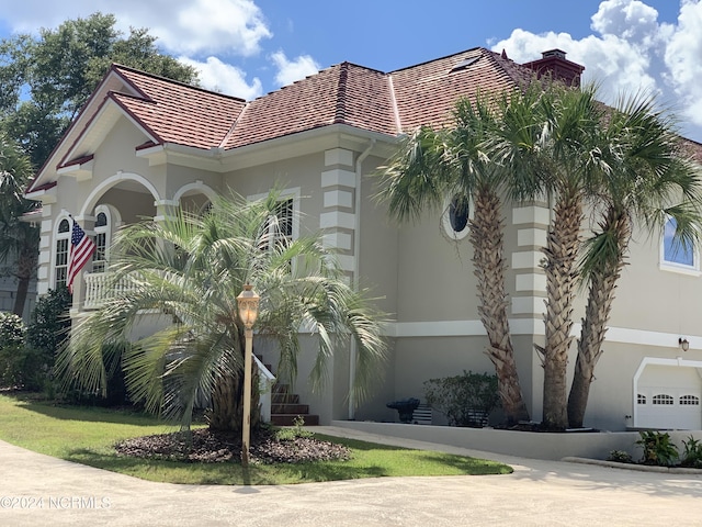 6424 River Vista Dr, Wilmington, NC 28412 - view of front facade featuring stucco siding, a chimney, and a tiled roof