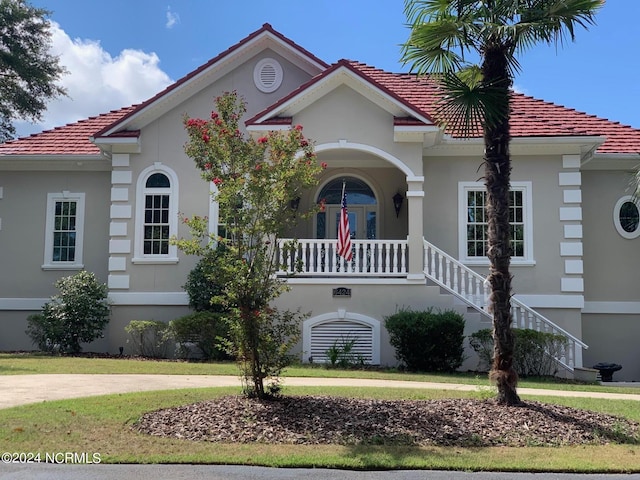 6424 River Vista Dr, Wilmington, NC 28412 - mediterranean / spanish-style house featuring a tiled roof, stairway, a porch, stucco siding, and a front yard